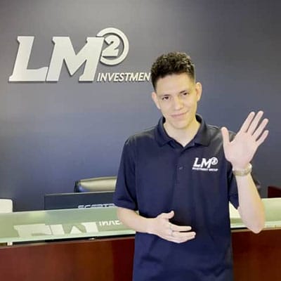 A man in a blue shirt standing in front of a sign that says lmm investor.