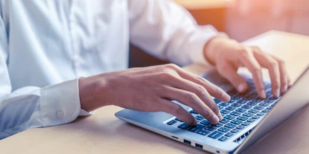 A man is typing on a laptop computer.
